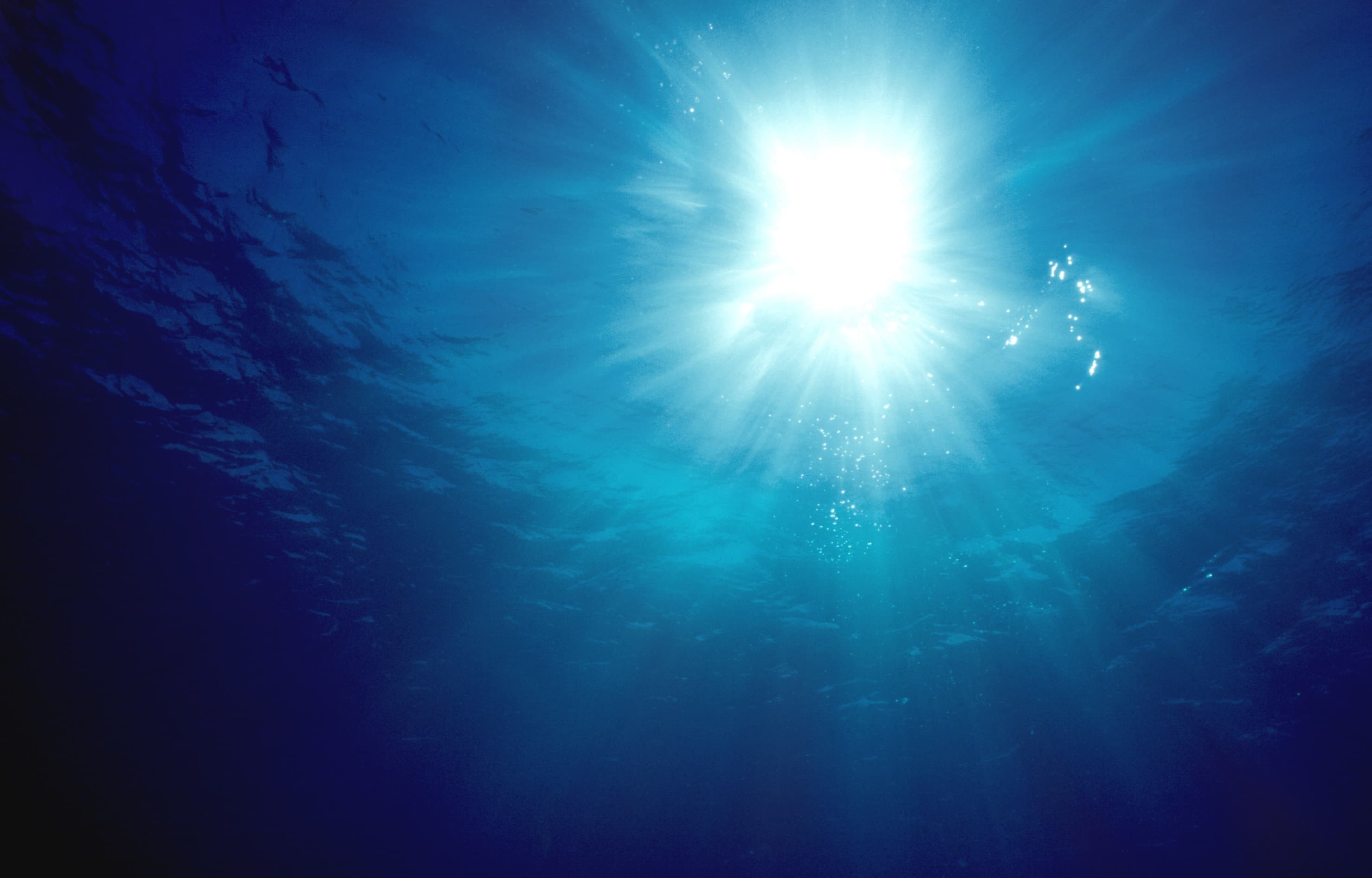 Sonnenstrahlen dringen tief ins dunkle blaue Meerwasser ein