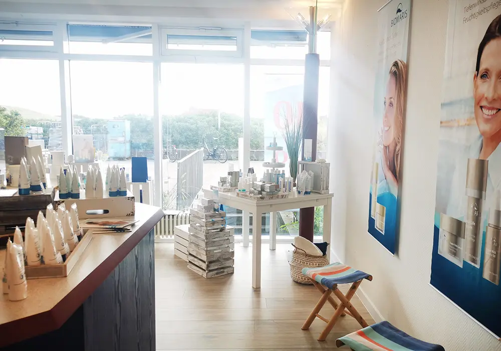 BIOMARIS Shop Baltrum Verkaufsfläche mit BIOMARIS-Produkten vor großen Fenstern mit Ausblick ins Grüne