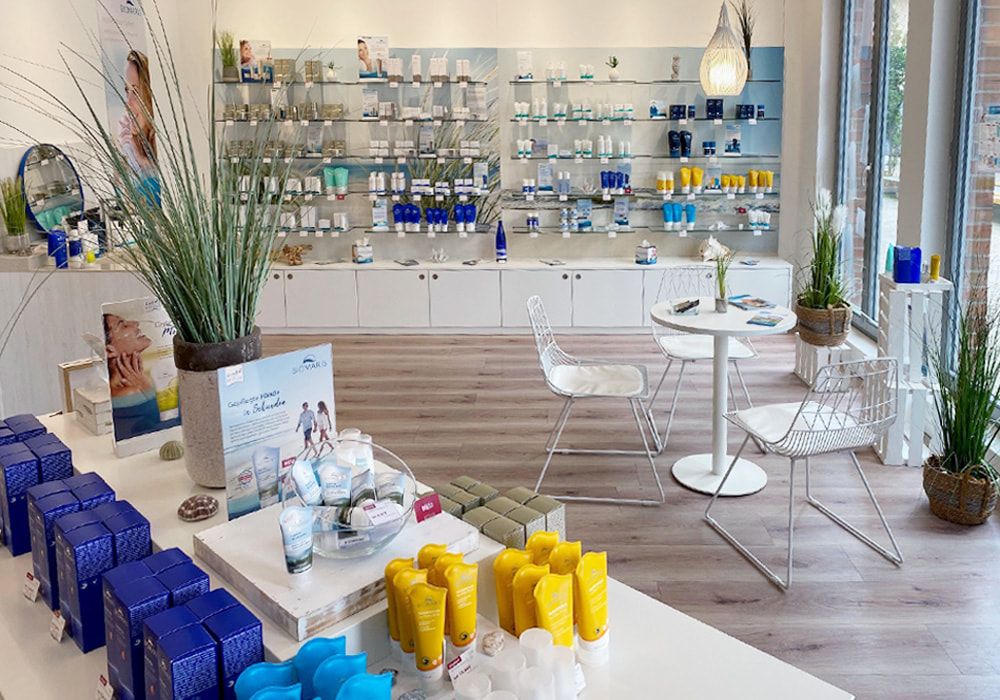 Heller Verkaufsraum mit Kosmetikregalen, Produkten und Sitzbereich im BIOMARIS-Shop 